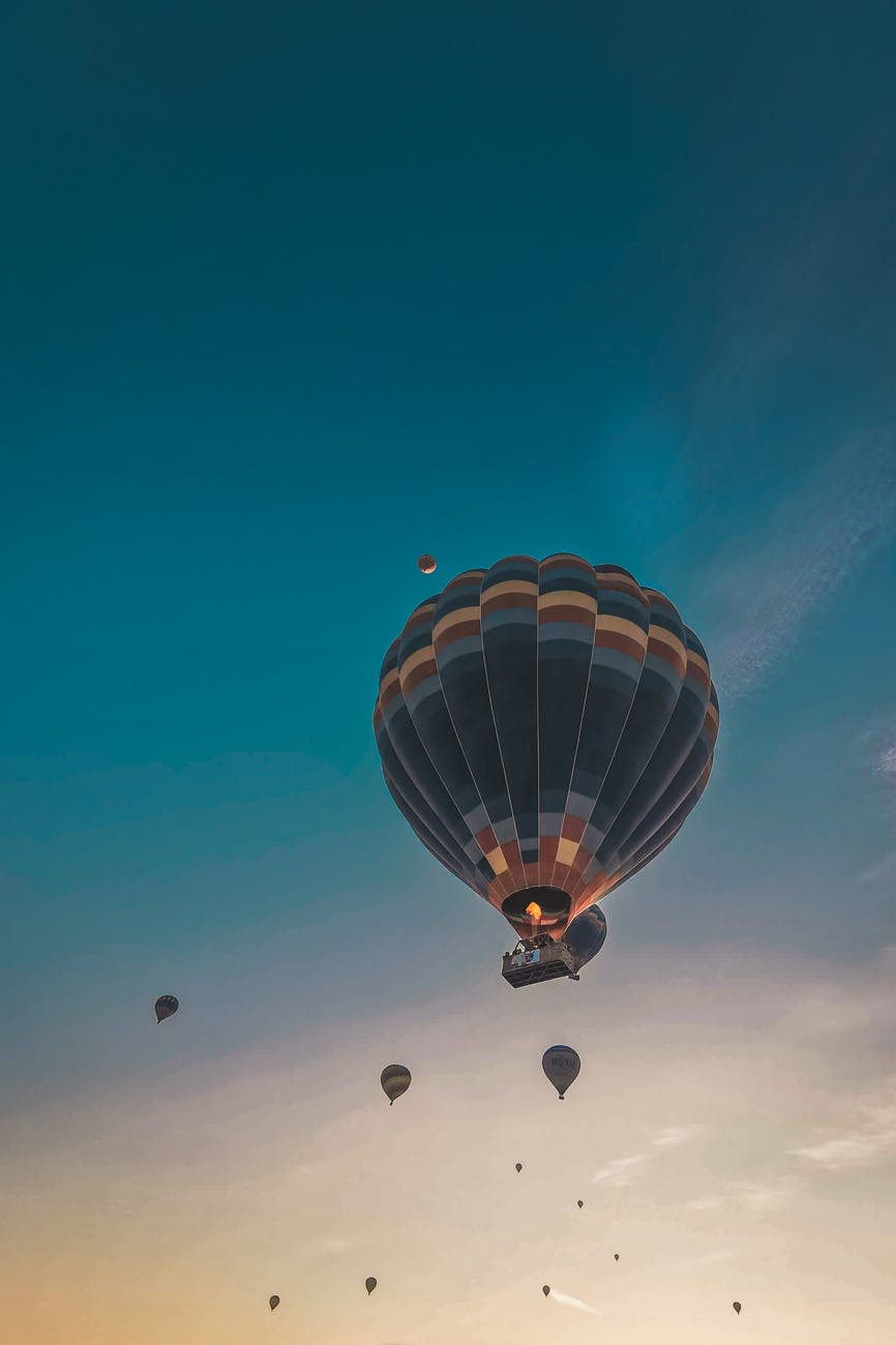 air balloons flying in bright sky at sunset